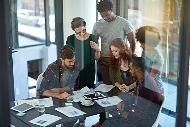 Group of diverse professionals collaborating around a table, analyzing documents and discussing wellness marketing strategies for Carolina Hyperbaric & Wellness.