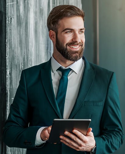 Smiling man in a teal suit holding a tablet, representing the professional team at Carolina Hyperbaric & Wellness.